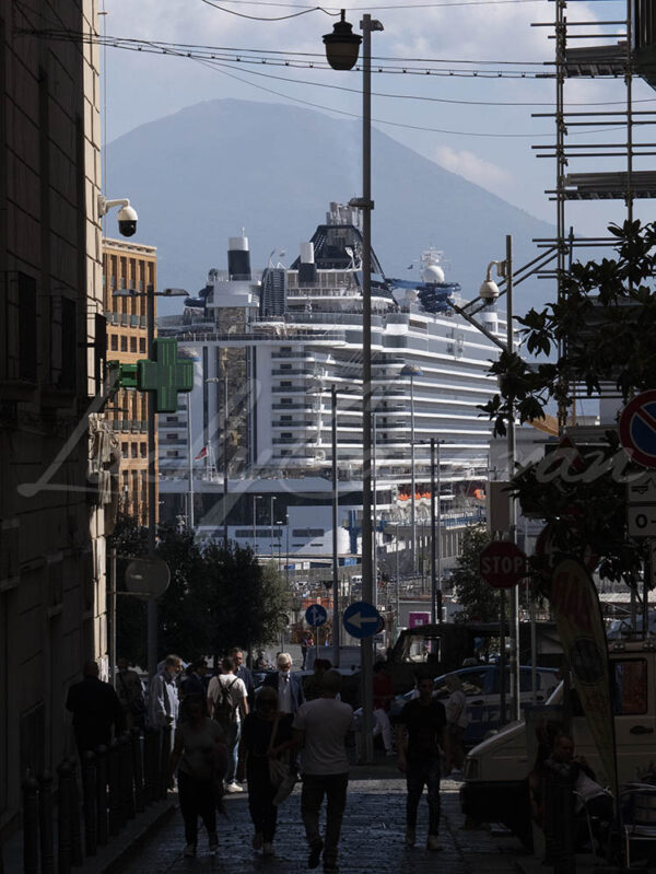 View from a narrow street on the port of Naples with a cruise ship and the Vesuvius, Italy