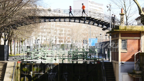 Joggers on the metal footbridge at the locks of La Villette in Paris