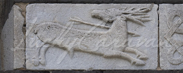 Carved stone representing a hunting scene on the façade of the 12th century Santa Maria del Tiglio Chapel in Gravedona, Lake Como, Italy