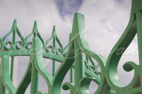 Green wrought iron gate with inverted hearts on a sky background