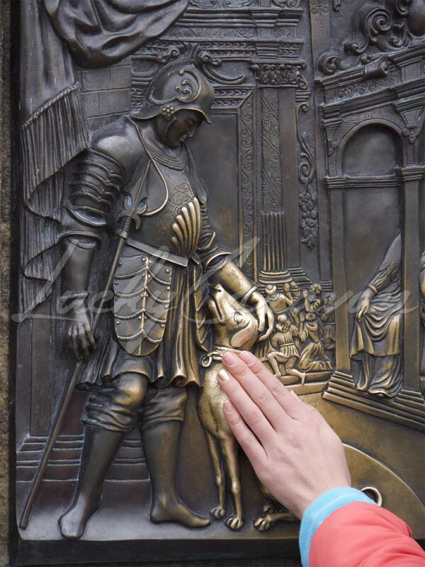 Veneration of a brass bas relief on the Charles Bridge in Prague, Czech Republic