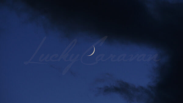 Dark clouds revealing the moon crescent