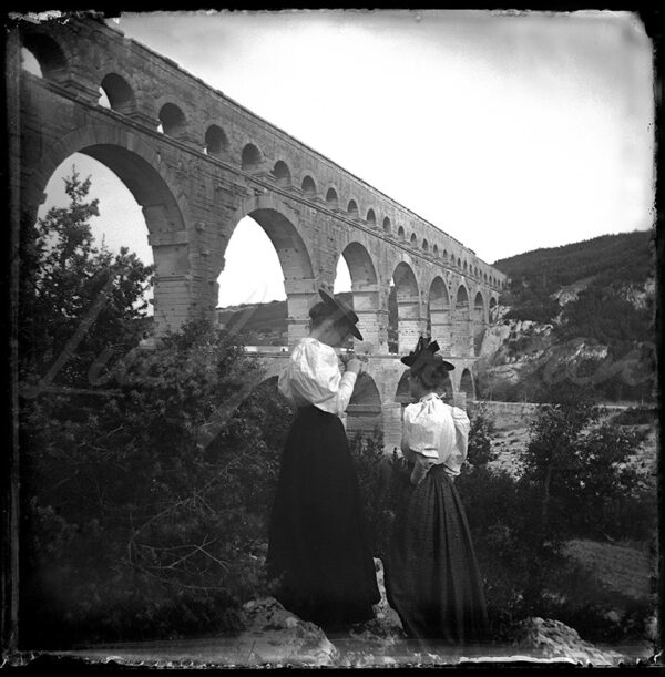 Two elegant women in front of the Pont du Gard circa 1900.