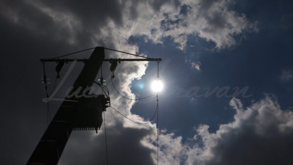 Sun disappearing above an electric pole