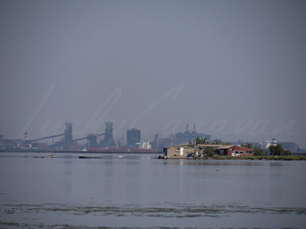 Rudimentary houses in front of industrial facilities.