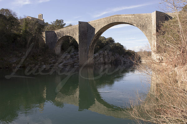 The Saint-Étienne d'Issensac bridge, built of local limestone, spans the Hérault river near the Saint-Étienne d'Issensac chapel, Occitania, southern France.