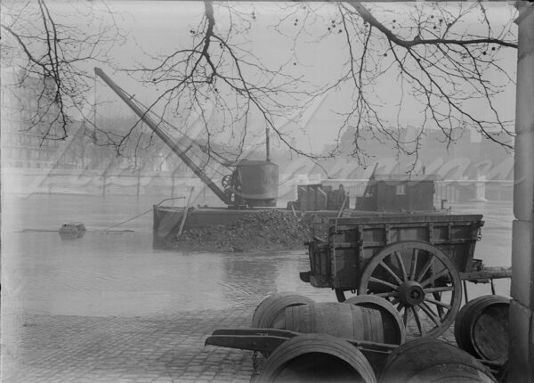 Barge and loading crane for river transport, on a flooded wharf in Paris, circa 1910