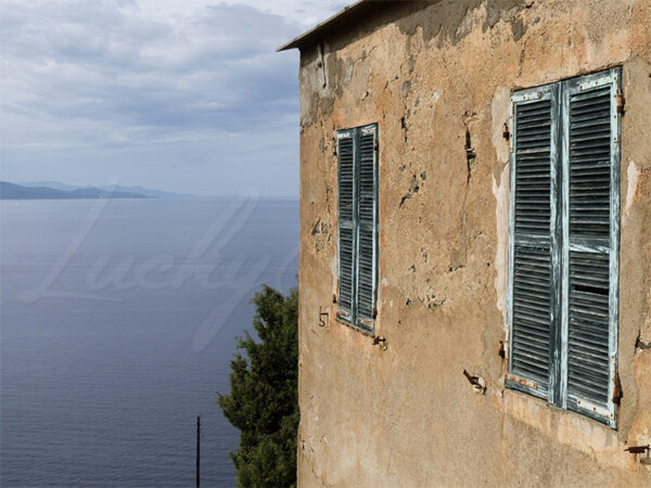 Abandoned house with green shutters overlooking the Mediterranean Sea