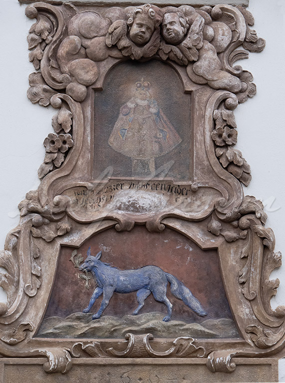 Pediment with blue wolf and allegorical figure in ceremonial dress.
