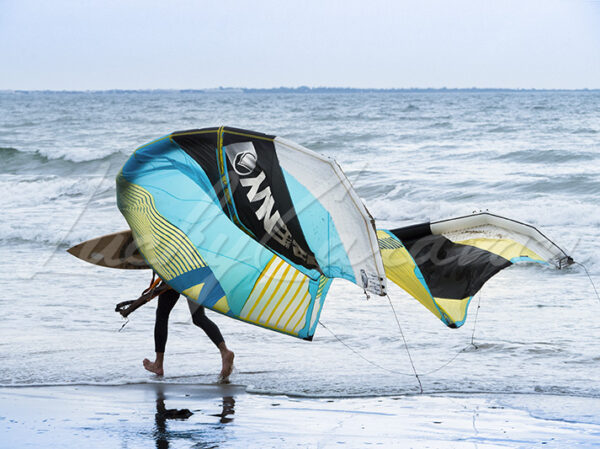 Birdman. Young man running on a Mediterranean beach with his kitesurfing equipment