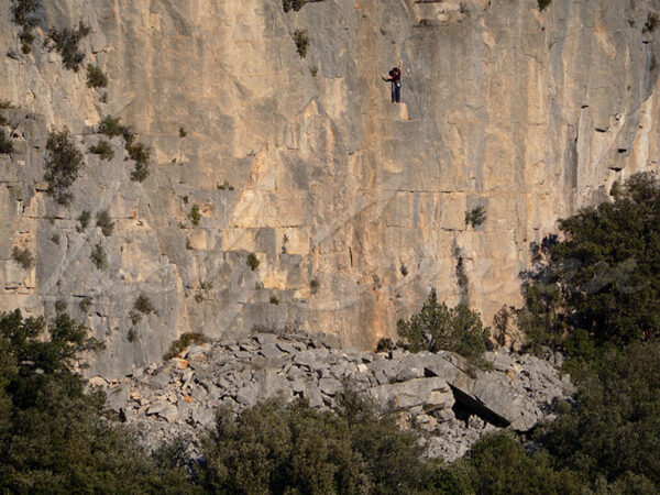 Solitary mountaineer in the middle of a difficult climb.