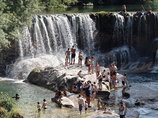 Vacationers bathing at a mountain waterfall.