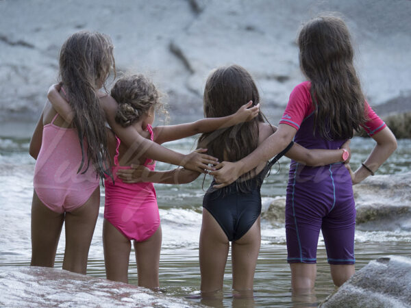 Four young girls holding each other in sign of friendship in a fresh mountain stream