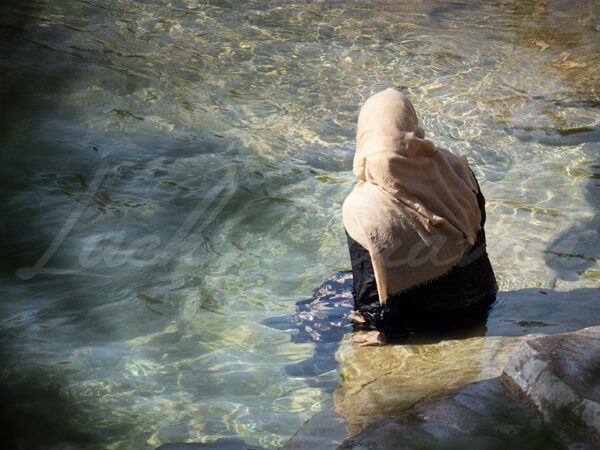 Muslim woman cooling off in the crystal clear waters of a river.