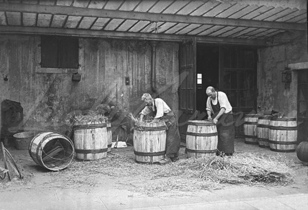 Two coopers making wooden barrels in a workshop, circa 1920
