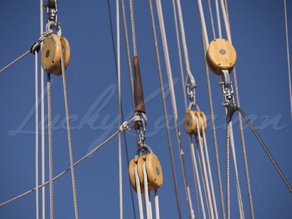 Wooden pulleys. Detail of the rigging of a traditional sailboat on a blue sky background