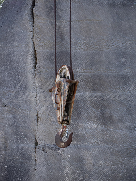 Old rusted crane hook in a stone quarry.