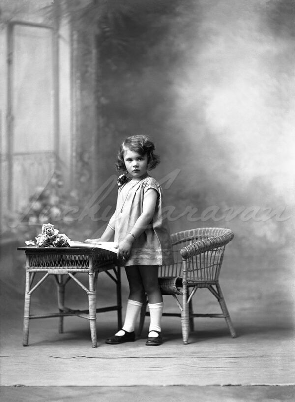 Little girl and flowers in a photographer's studio in the early 20th century