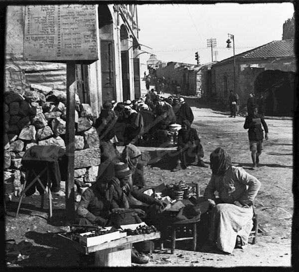Palestine. Stalls in an old neighborhood of Jerusalem in the early 20th century. A sign in Hebrew advertises tours of touristic sites.